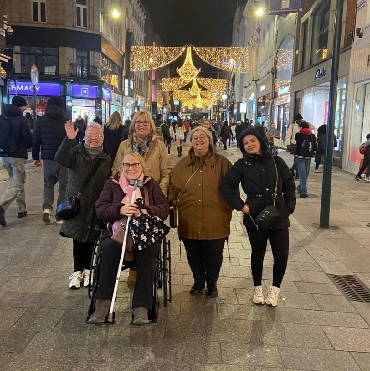 Group enjoying an evening out on Grafton Street Dublin with rented wheelchair under festive Christmas lights